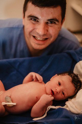 Отец счастливо держит новорожденного ребенка в больнице после успешных родов